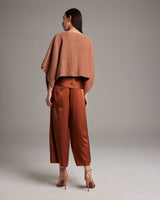 Model wearing a shimmering copper crop top and rust pants from the back