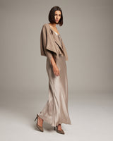Model wearing a taupe bolero over a satin slip dress
