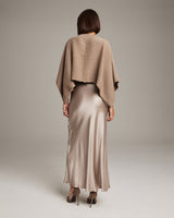Model wearing a camel bolero over a satin slip dress from the back