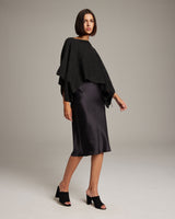 Model wearing a black alpaca crop top with a satin skirt and black heels.