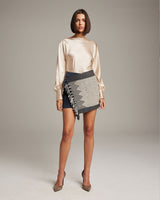 Model wearing a Diamante Mini Wrap Skirt with a diamond pattern and fringe