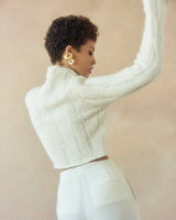 Model wearing a white ribbed cropped sweater, showing the back view