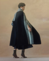 Model wearing a black and ivory Lineas cloak, showcasing its design and movement.