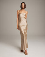 Model wearing a liquid silk slipdress in gold, showcasing its elegant design.