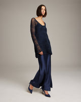 Model wearing a navy loose knit linen sweater with a long satin skirt and heels.