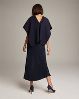 Model wearing a navy poncho-style Manta Araña, showing back view.