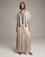 Model wearing a gray manta with Araña symbol, styled with a long skirt and heels.