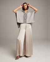 Model wearing a hand-loomed Manta Araña poncho with a geometric design, styled with wide-leg pants.