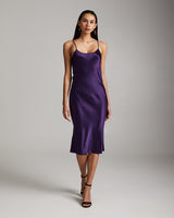Model wearing a purple midi slip dress with spaghetti straps