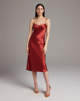 Model wearing a red satin midi slip dress with spaghetti straps