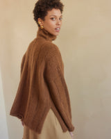Model wearing a brown oversized ribbed knit sweater with a side slit