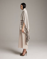 Model wearing the Petite Cascade Wrap in ivory with striped design, side view