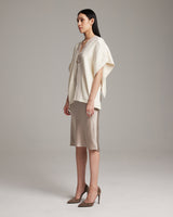 Model wearing a cream Copihue Manta over a satin skirt