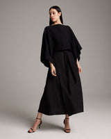 Model wearing a black textured cotton crop top with a long black skirt and heels.