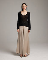 Model wearing a black sweater and beige silk palazzo pants