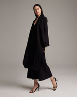 Model wearing a black Linen Featherlight Wrap Blouse, standing in a pose.