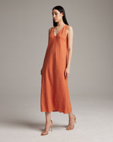 Model wearing a linen V neck dress in persimmon color