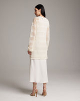 Model wearing a loose knit linen sweater in ivory, showing the back view.