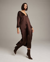 Model wearing a brown silk tunic dress with a deep V-neck and stylish boots.