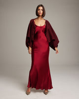 Model wearing a burgundy bolero over a red satin dress