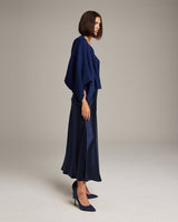 Model wearing a navy bolero over a satin dress and heels