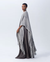 Model wearing a long chevron duster with fringe, in black and ivory colors.
