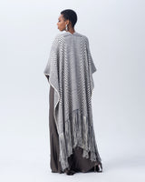 Model wearing a long chevron duster with fringe in black and ivory, viewed from the back