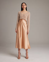 Model wearing a painted loose knit cropped sweater with a satin skirt