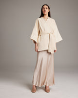 Model wearing an ivory Samurai Jacket with a detachable belt, paired with a satin skirt.