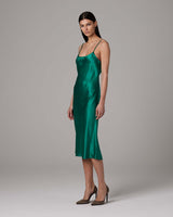 Model wearing a green satin midi slip dress with spaghetti straps