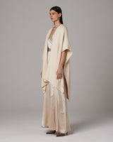 Model wearing a cream-colored alpaca duster over a satin outfit