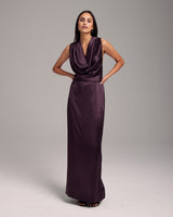 Model wearing a backless halter dress in aubergine silk charmeuse