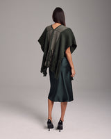 Model wearing a dark green Lineas Fringe Manta with fringes, back view