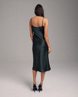 Back view of a model wearing a green midi slip dress with thin straps.