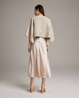 Model wearing a heathered beige bolero over a satin skirt