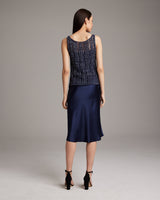 Model wearing a navy Lace Knit Tank from the back, paired with a satin skirt.