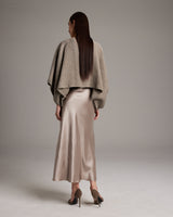 Model wearing a shimmering cotton bolero over a satin skirt from the back
