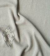 Close-up of Araña Blanket in Ivory showing texture and sacred symbol