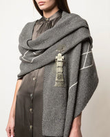 Model wearing a gray shawl with a ceremonial pin attached, showcasing its design and use.