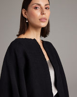 Model wearing a black hand-loomed textile crop bolero with a textured weave.