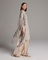 Model wearing a Lace Fringe Manta in taupe with fringed details, paired with a satin skirt.