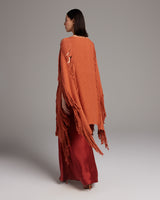 Model wearing an orange Lace Fringe Manta with fringe details, paired with a red skirt.