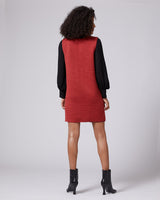 Back view of a model wearing a sleeveless red Che dress with black sleeves