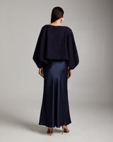 Model wearing a navy bolero over a satin skirt from the back