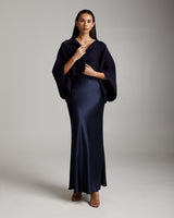 Model wearing a navy bolero over a satin skirt