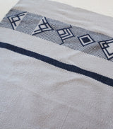 Close-up of a handwoven textile featuring geometric patterns in navy and beige.