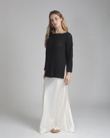 Model wearing a black boat neck relaxed sweater with side slits