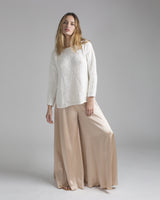 Model wearing an ivory relaxed sweater with boat neckline and palazzo pants