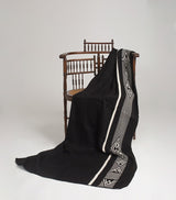 Black alpaca blanket draped over a chair with decorative edge