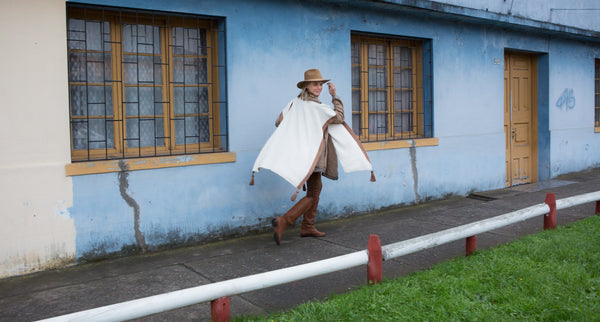 Angela Lindvall walking in a white poncho outside a blue building
